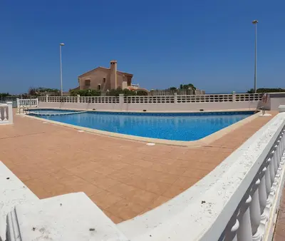 a swimming pool next to a white fence at Vacansis Adosado Marenyet in Cullera
