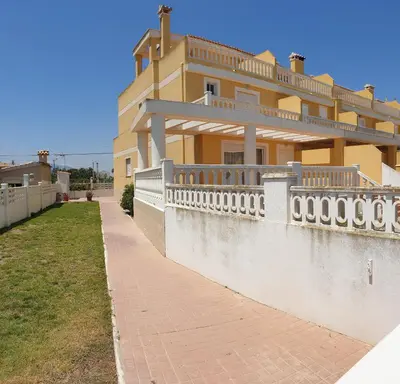 a large yellow house with a fence and a sidewalk at Vacansis Adosado Marenyet in Cullera