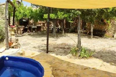 a backyard with a blue swimming pool under an umbrella at La Casa de Piedra, una ventana al paraíso in Matet