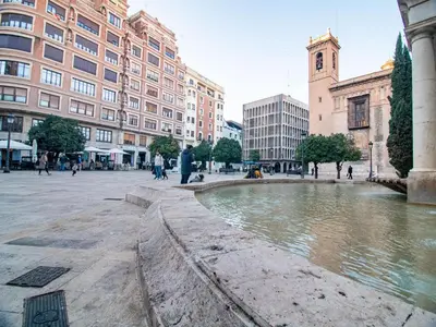 a fountain in a city with buildings and people walking at MD Vitoria City Center in Valencia