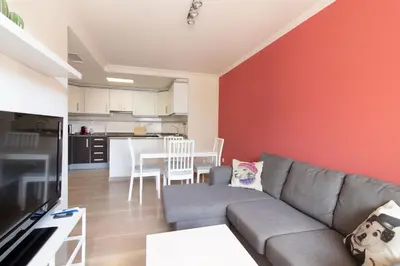 a living room with a gray couch and a red wall at Global Vacacional, Apartamento a 200m de la playa de Puerto de Sagunto in Puerto de Sagunto