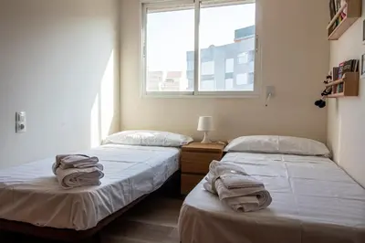 two beds in a room with a window at Global Vacacional, Apartamento a 200m de la playa de Puerto de Sagunto in Puerto de Sagunto