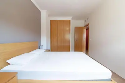 a bedroom with a large bed with white sheets at Global Vacacional, Apartamento a 200m de la playa de Puerto de Sagunto in Puerto de Sagunto