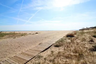 a boardwalk in the sand at the beach at Global Vacacional, Apartamento a 200m de la playa de Puerto de Sagunto in Puerto de Sagunto