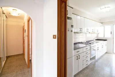 a white kitchen with white cabinets and a door at Global Vacacional, Apartamento con terraza y piscina a un paso de la playa in Canet de Berenguer