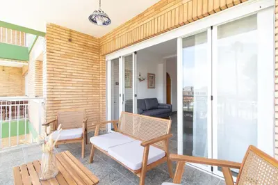 a building with palm trees and a playground at Global Vacacional, Apartamento con terraza y piscina a un paso de la playa in Canet de Berenguer