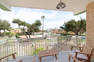 a porch with two chairs and a table and a bench at Global Vacacional, Apartamento con terraza y piscina a un paso de la playa in Canet de Berenguer