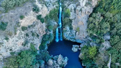 an aerial view of a waterfall in a canyon at La Gata Mala in Navarrés