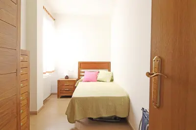 a small bedroom with a bed and a dresser at Global Vacacional, Ático con 2 terrazas en la playa Puerto de Sagunto in Puerto de Sagunto