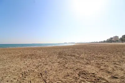 a sandy beach with the ocean in the background at Global Vacacional, Ático con 2 terrazas en la playa Puerto de Sagunto in Puerto de Sagunto