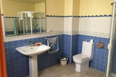 a blue tiled bathroom with a toilet and a sink at Casa de Pueblo en Navarres in Navarrés
