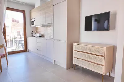 a kitchen with white cabinets and a tv on a wall at Slow Home Apartments in Valencia