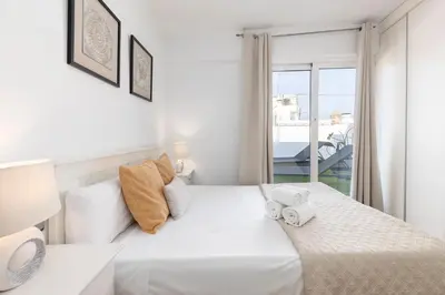 a white bedroom with a bed and a balcony at Travel Habitat - Ático Centro in Valencia