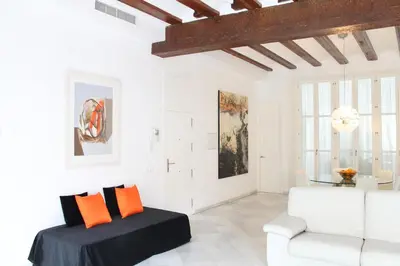a white living room with a white couch and orange pillows at Apartamento Reina Catedral in Valencia