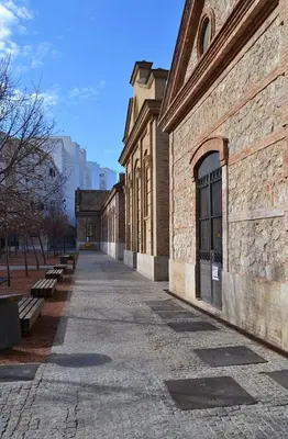 an empty sidewalk next to a brick building with benches at Cozy flat in La Petxina B in Valencia