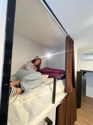 a woman sitting on top of a bed at Beach & Arts Hostel Valencia in Valencia