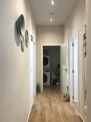 a hallway with a white wall with two clocks on it at Apartamento equipado playa Valencia OnesDeMar in Valencia