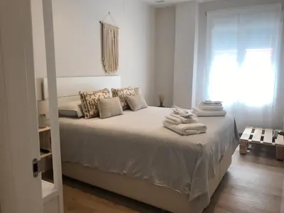 a white bedroom with a bed with towels on it at Apartamento equipado playa Valencia OnesDeMar in Valencia