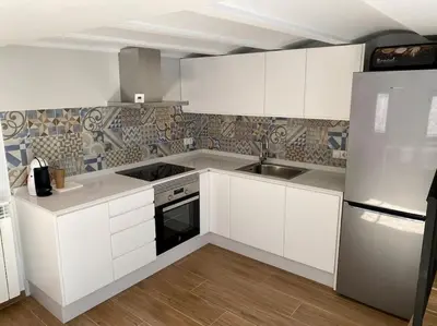 a kitchen with white cabinets and a sink and a refrigerator at VILLA SOL Casa con cueva privada y vistas a la Iglesia in Requena