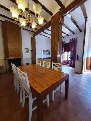 a dining room with a wooden table and white chairs at CASA BAUTISTA - ROTGLÀ in Rotglá y Corbera