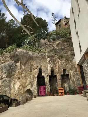 a rock wall with a pink door next to a building at CASA PORTALICO in Jérica