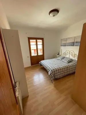 a bedroom with a bed and a wooden floor at Precioso adosado con parking a 100 metros de la playa in Playa de Mar