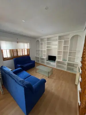 a living room with a blue couch and white shelves at Precioso adosado con parking a 100 metros de la playa in Playa de Mar