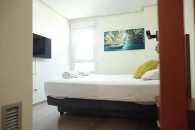 a bedroom with a large white bed with towels on it at Best Valencia Beach Rooms-Shared Flat in Valencia