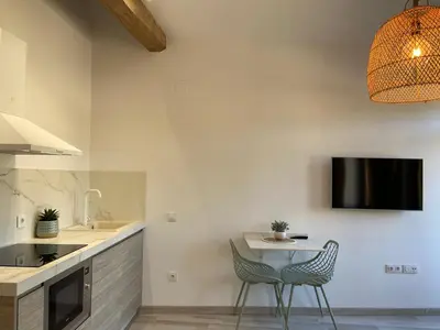 a kitchen with a table and two chairs and a tv at Apartamento Casa Anselmo La cambra in Losa del Obispo