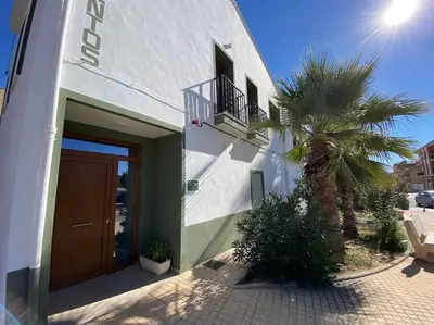 a white building with a door and a palm tree at Apartamentos LOSA RURAL in Losa del Obispo