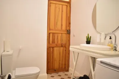 a bathroom with a wooden door next to a toilet and a sink at Gran apartamento cerca de Ruzafa in Valencia