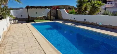 a swimming pool in a yard with a white wall at Casa Azahara your Valencian Villa in Macastre