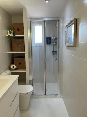 a white bathroom with a shower and a toilet at La casita de Jimena in Valencia