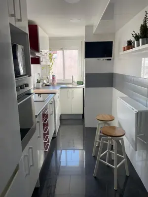 a kitchen with white cabinets and two stools in it at La casita de Jimena in Valencia