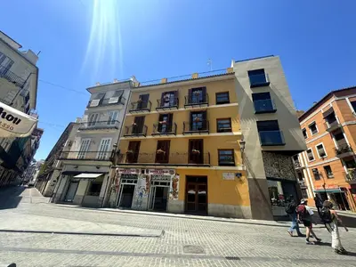 a tall yellow building with people walking in front of it at Precioso Apartamento en la Plaza del Tossal in Valencia