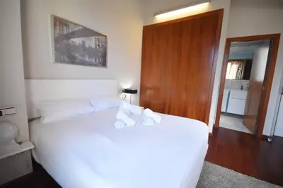 a bedroom with a white bed and a wooden door at Bello Apartamento en la Plaza del Tossal in Valencia