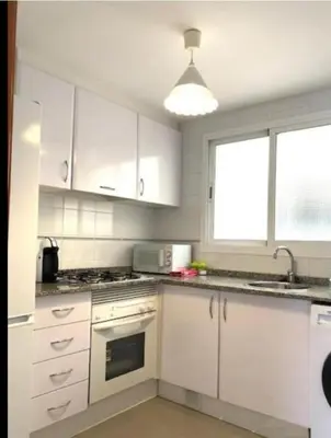 a kitchen with white cabinets and a stove top oven at UIM Mediterraneo Diagonal 16 Wfi in Puerto de Sagunto