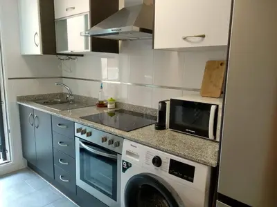 a kitchen with a washing machine and a microwave at Apartamento acogedor en playa de Moncofa in Moncófar
