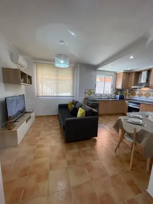 a living room with a black couch and a kitchen at UIM Mediterraneo PB Plomo 2 Wifi in Puerto de Sagunto