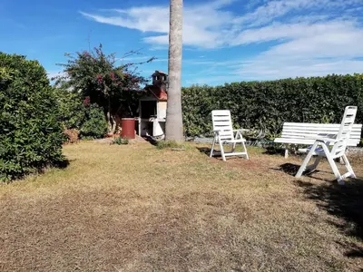 two white benches sitting in the grass next to a pole at Oasis Solo Familias Serviplaya in Casas Las Basas