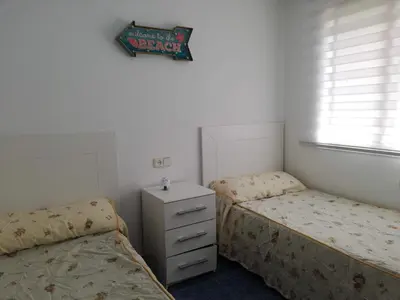 a bedroom with two beds and a sign on the wall at Oasis Solo Familias Serviplaya in Casas Las Basas
