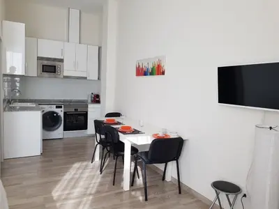 a white kitchen with a white table and chairs at Studio Picasso near the port and beach in Valencia