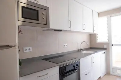 a kitchen with white cabinets and a sink and a microwave at Las Olas Solo Familias Serviplaya in Casas Las Basas