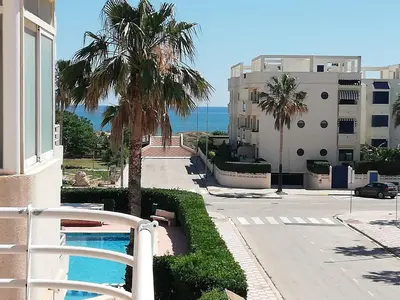 a building with a palm tree and a swimming pool at Las Olas Solo Familias Serviplaya in Casas Las Basas