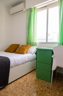a bedroom with a bed with green curtains and a window at Platja Puig in Valencia