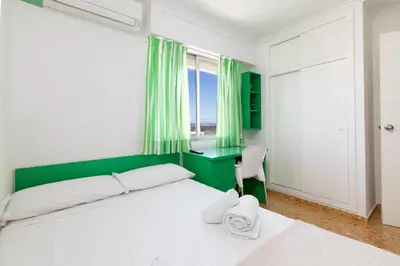 a bedroom with a bed and a desk and a window at Platja Puig in Valencia