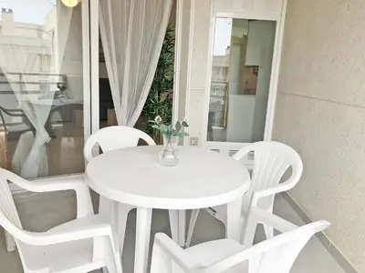 a white table with a vase with flowers on it at Global Vacacional, Increíble apartamento en la playa, Canet d'en Berenguer in Canet de Berenguer