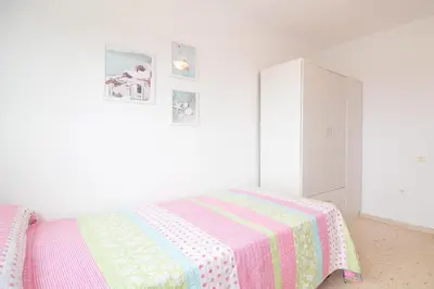 a white bedroom with a bed and a cabinet at Global Vacacional, Increíble apartamento en la playa, Canet d'en Berenguer in Canet de Berenguer