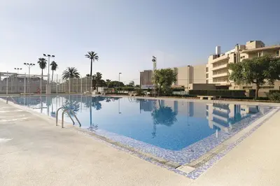 a large swimming pool with blue water in a city at Global Vacacional, Increíble apartamento en la playa, Canet d'en Berenguer in Canet de Berenguer