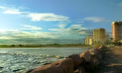 a beach with rocks and the ocean and buildings at Pobla-Mar in Valencia